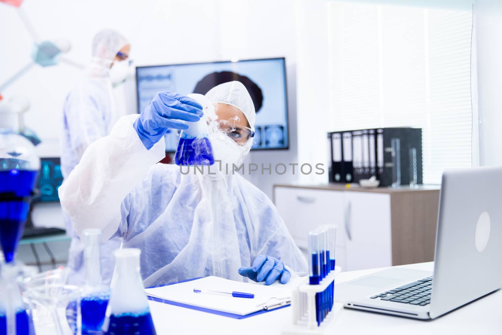 Chemist holding a container of blue liquid from which comes a white smoke.