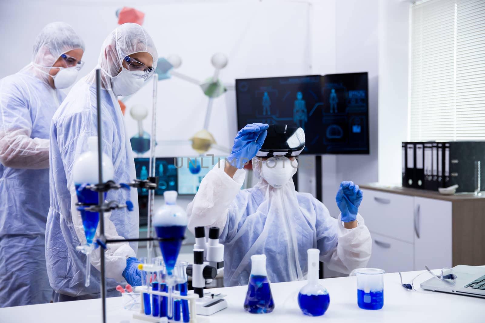 Team of scientist using virtual reality goggles for scientific research in their laboratory. Smoking blue liquid.