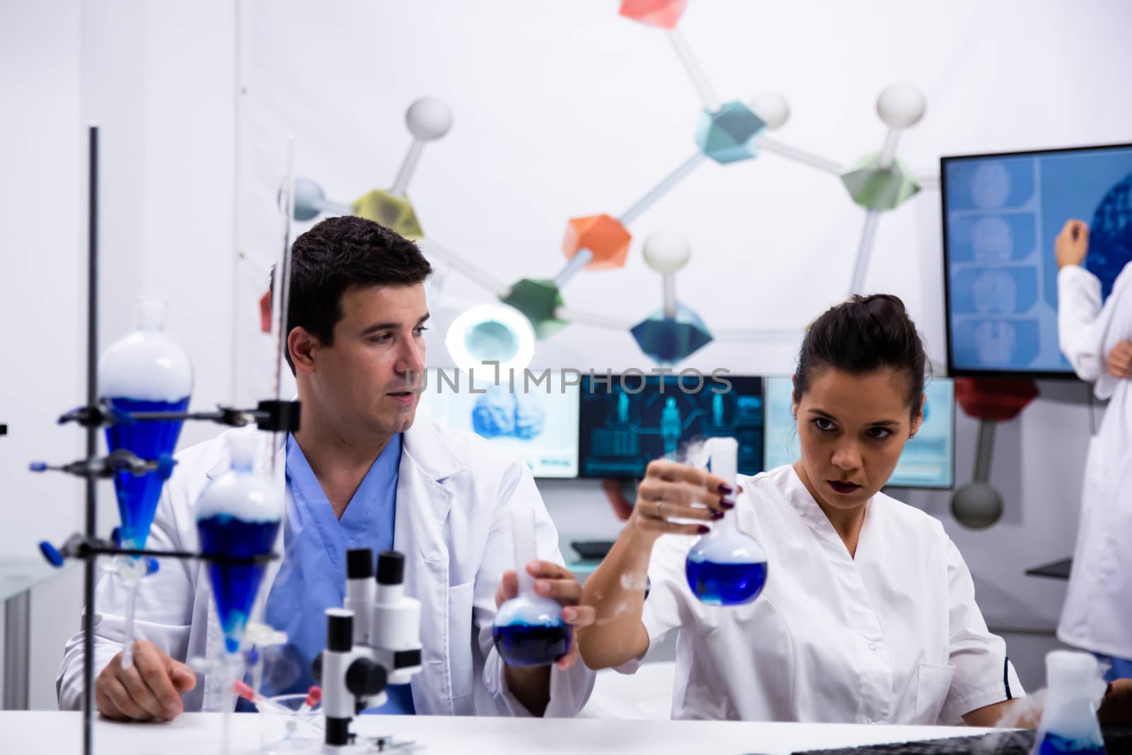 Female scientist in white coat holding a test tube with blue solution in modern research laboratory.