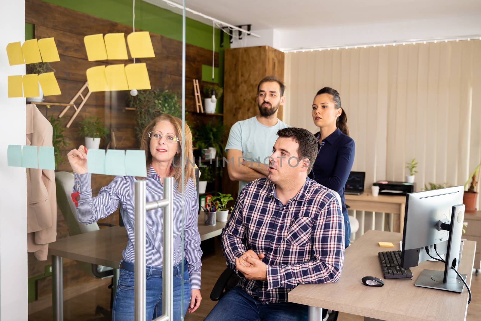 Manager explaining to the team new company strategy on a window with stickers