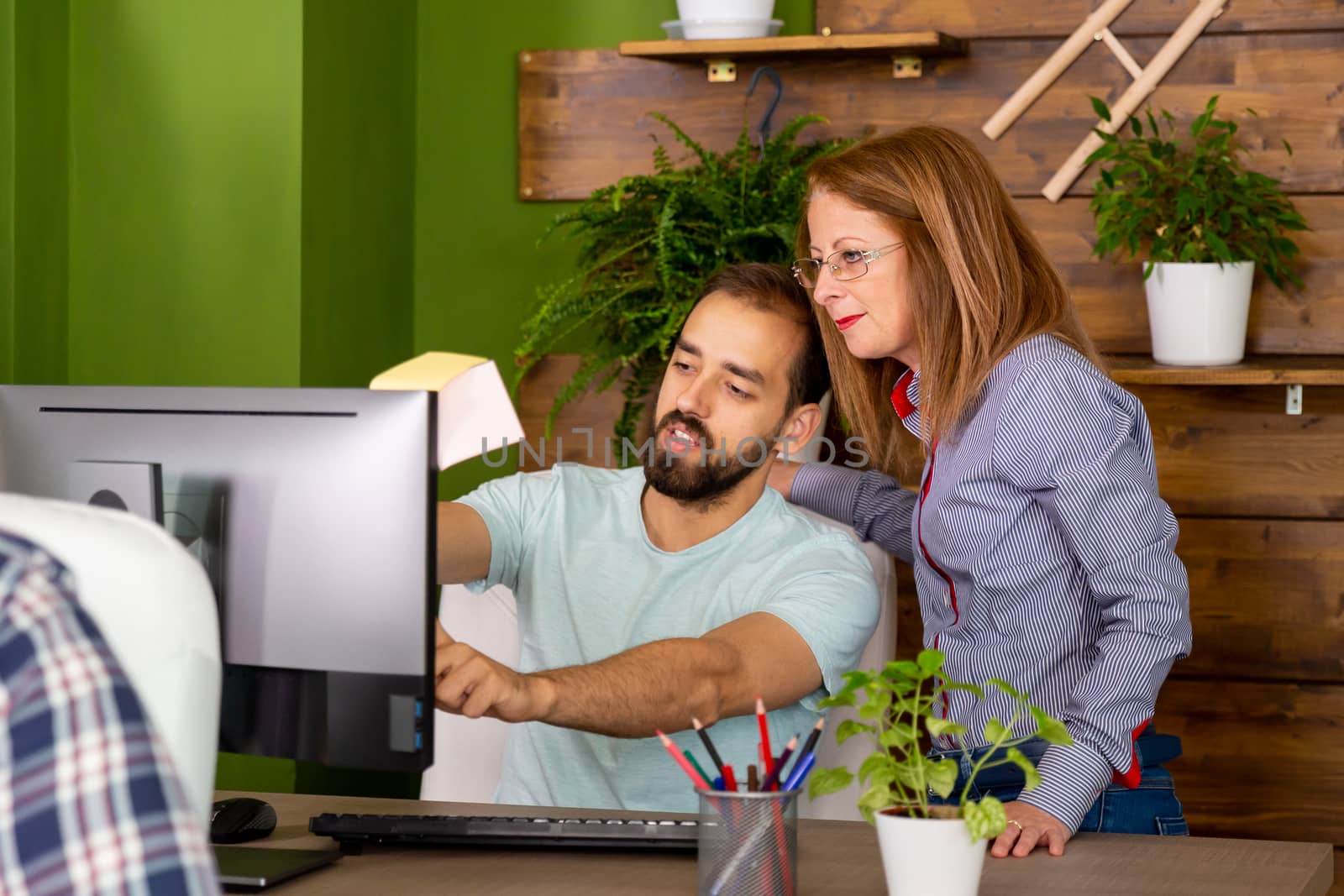 Two colleagues look to screen. . Start up company office