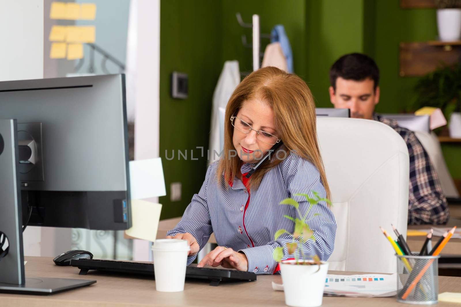 Woman talking on the phone and typing. And looking at the keyboard