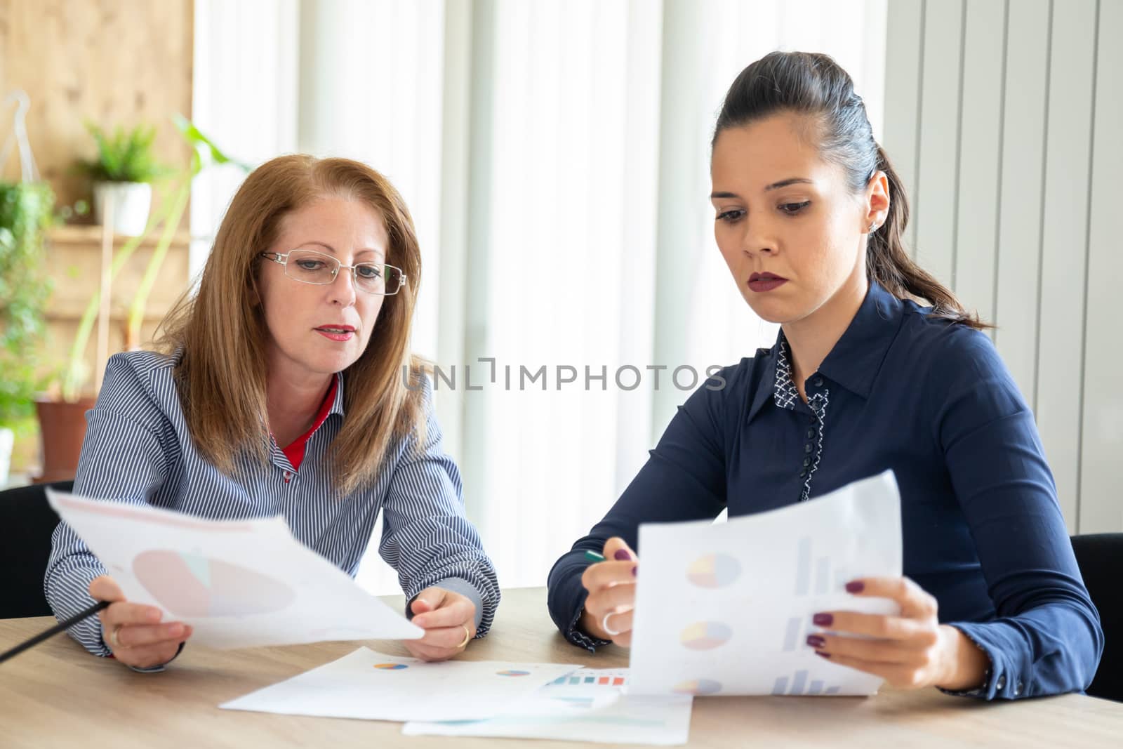 Two caucasus women are sitting with some sheets in front. New project trainee