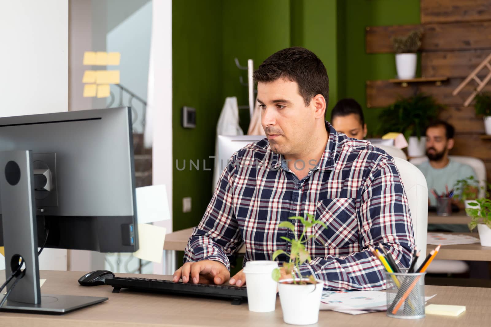 Young caucasian business man working looking serious at his computer monitor and typing. Smart young man.