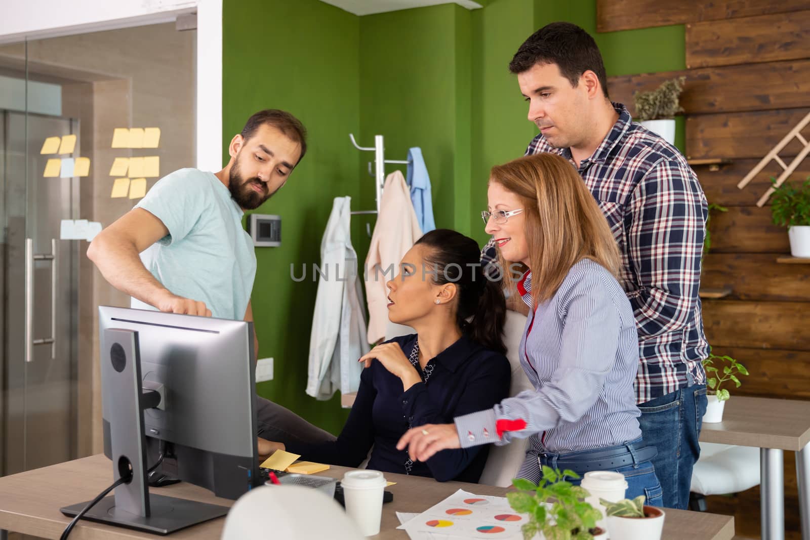 Adult business team in casual clothes brainstorming in front of computer screem