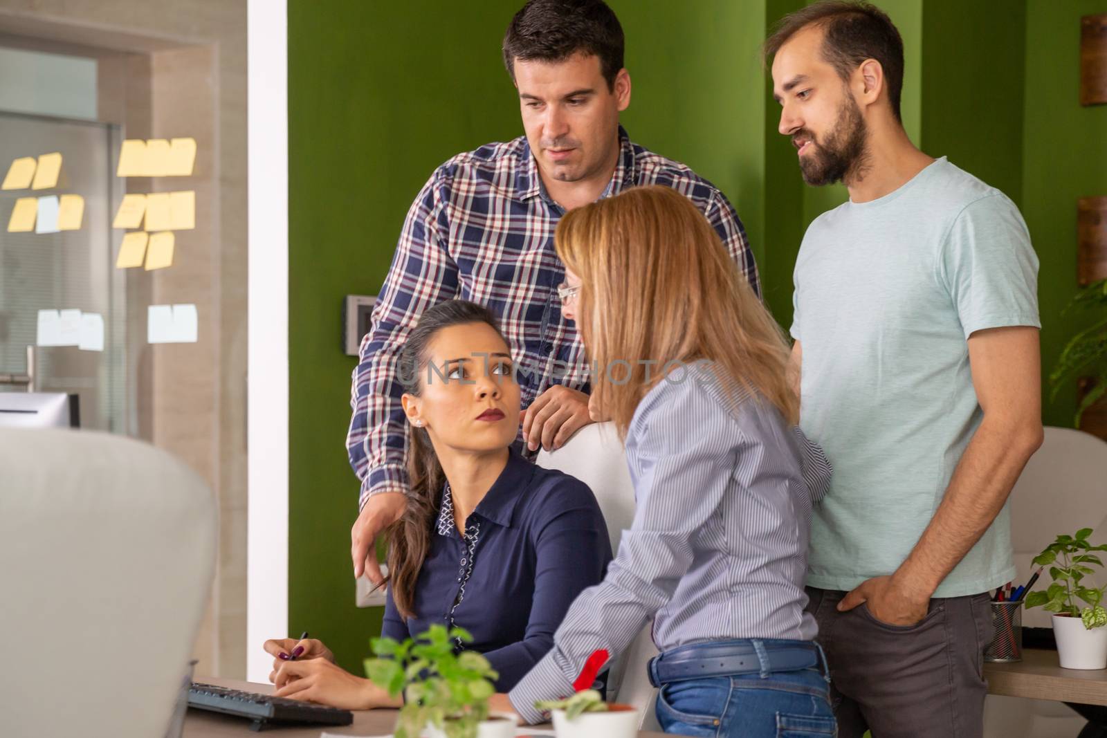 Young female manager having a conversation with her team in the office. Team discussing their strategy.
