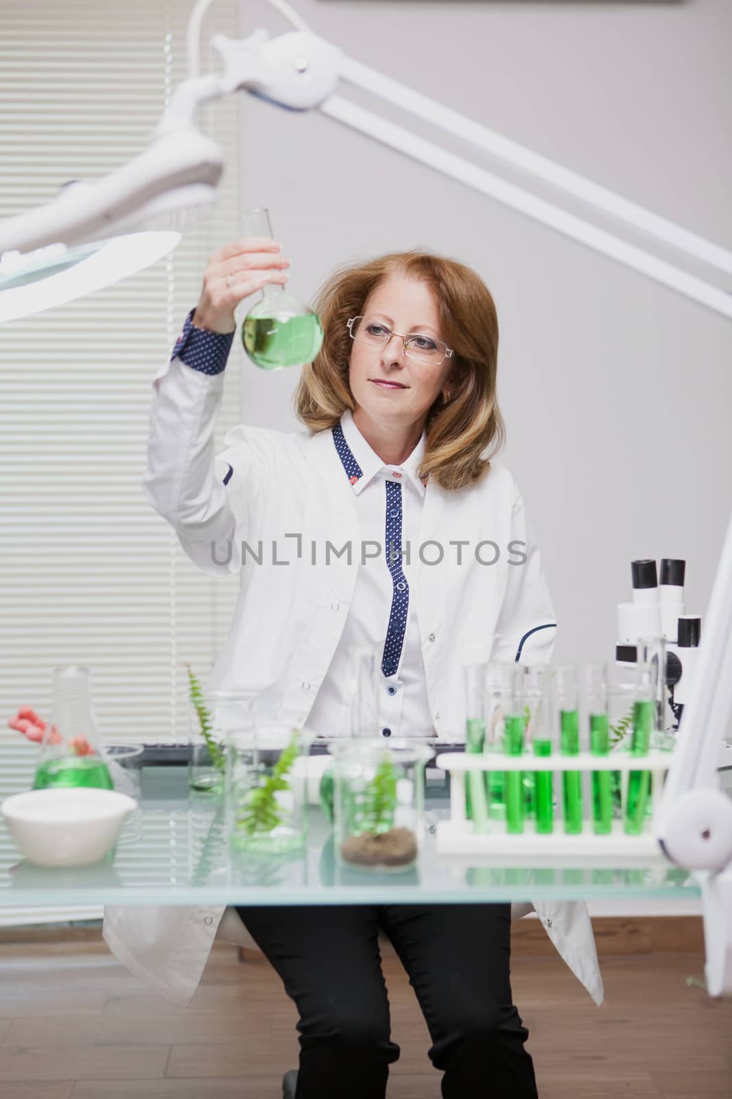 Portrait of middle age woman working in microbiology industry. Female scientis in laborator. Test tubes.