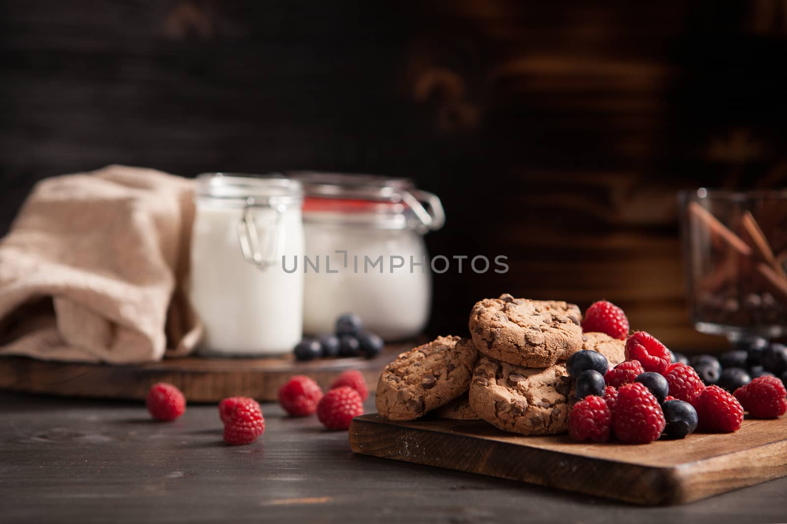 Freshly baked chocolate chips with tasty forest fruits on wooden plate. Tasty raspberry and blueberries.