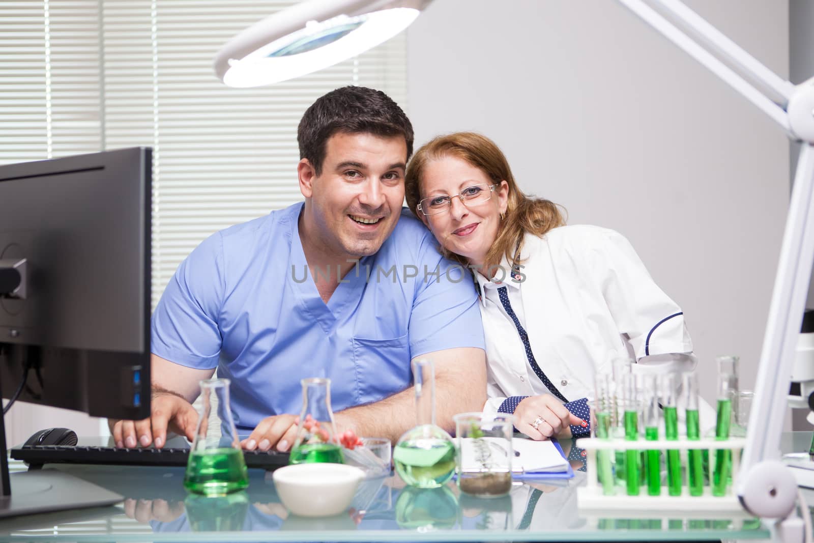Portrait of scientist woman with her assistant looking into the camera in their research lab. Research in human health