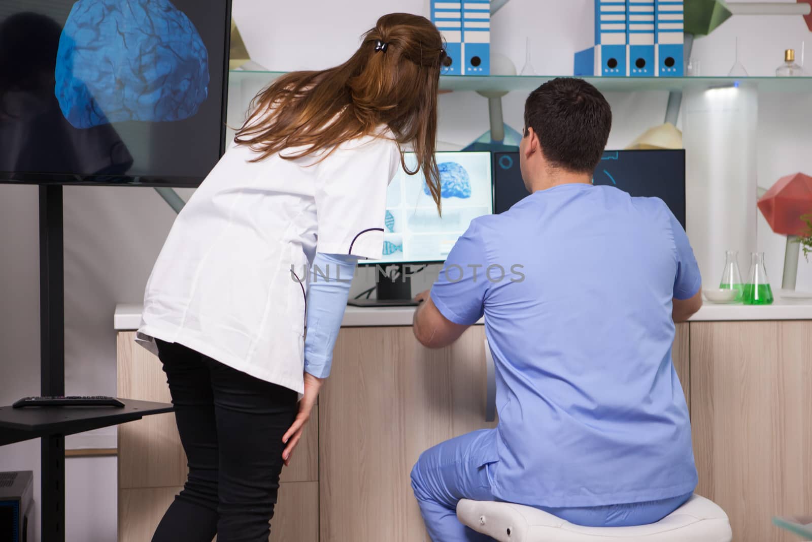 Female scientist working together with her assistant in microbiology laboratory. Biologist in factory.
