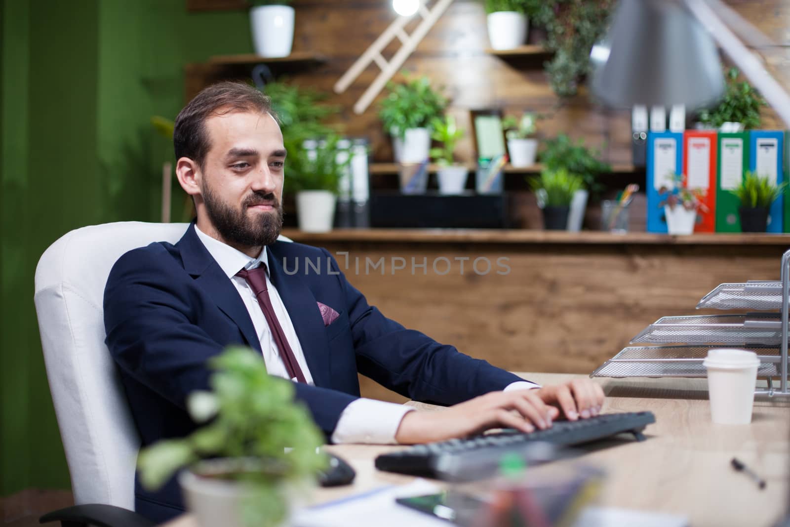 Confident young entreprenur working on his computer dressed in business suit. Handsome businessman.