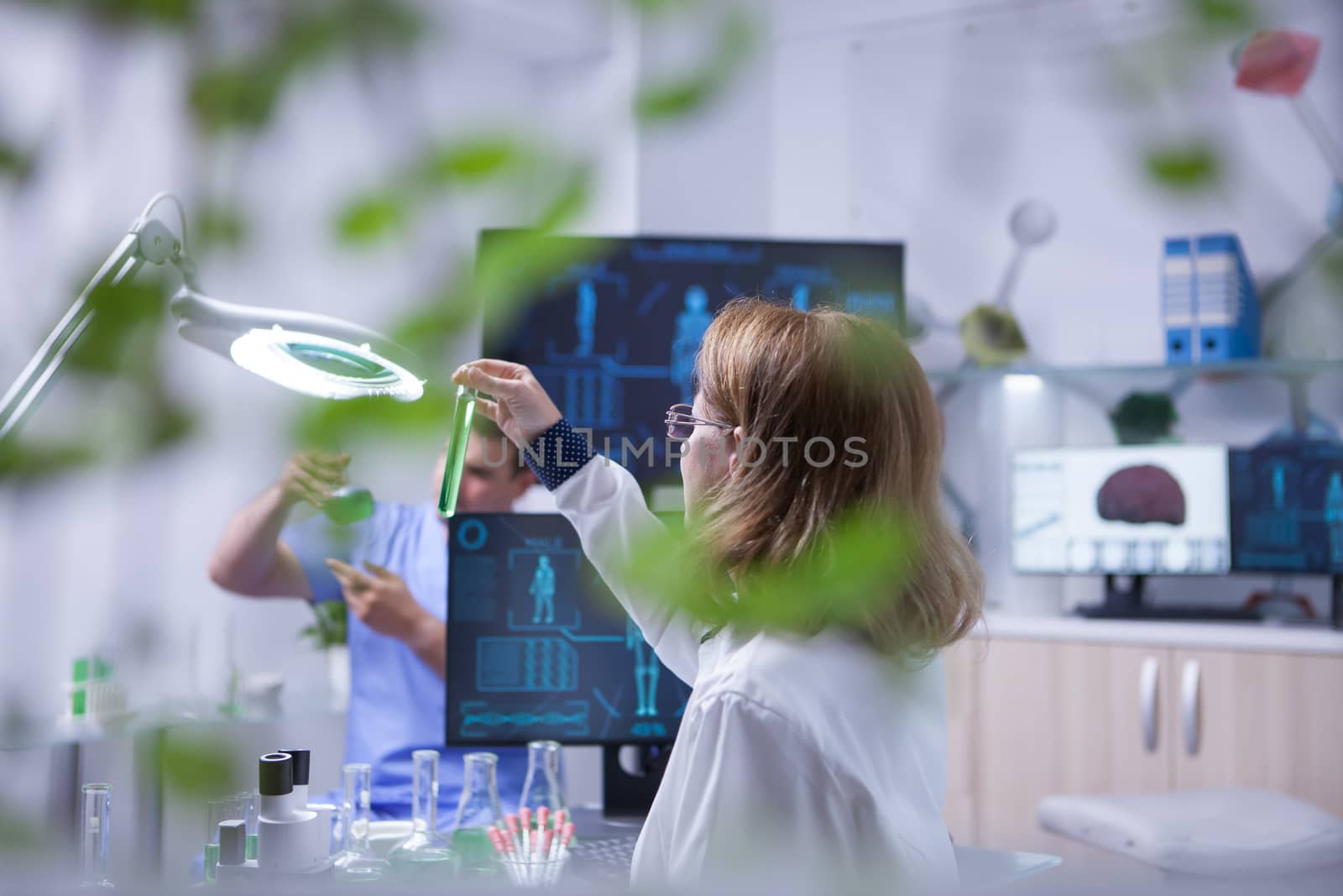 Female scientist holding and looking at a sample of liquid in a test tube. Academic scientist.