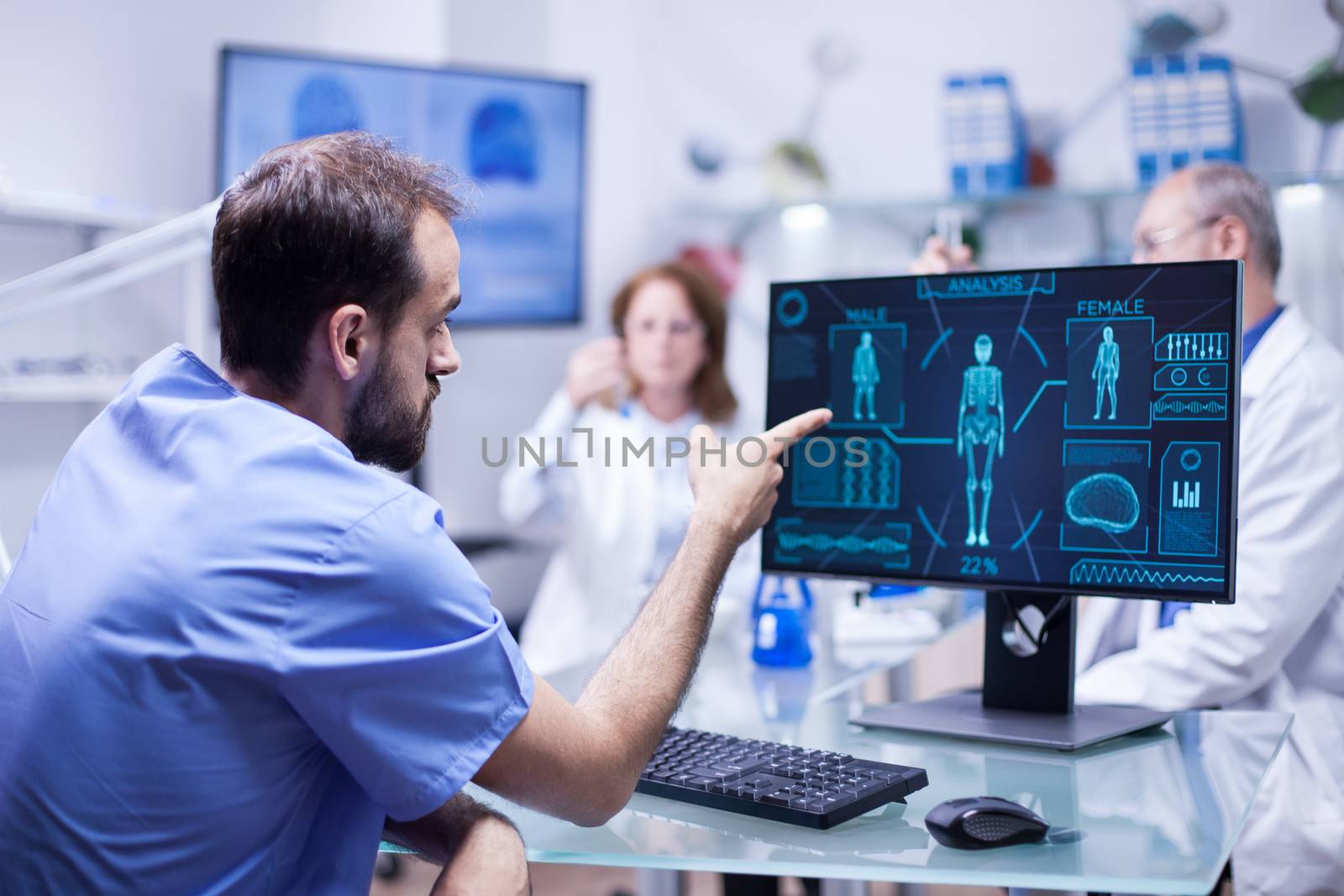 Young engineer in inovation center for body research pointing at monitor. Team of scientists in a innovation center.