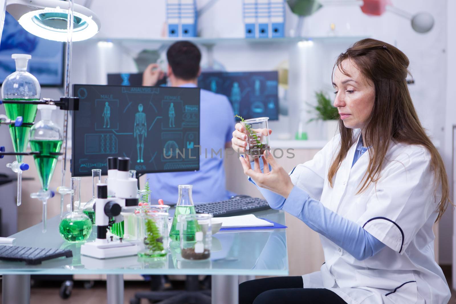 Female scientist with a microscope on her research lab. Test tubes.