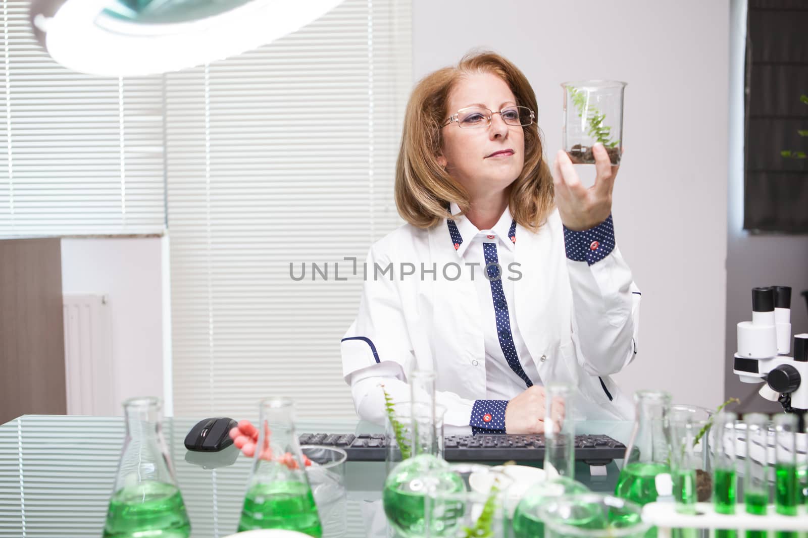 Academic scientist doing research on plants in microbiological lab. Test tubes with green solutions.
