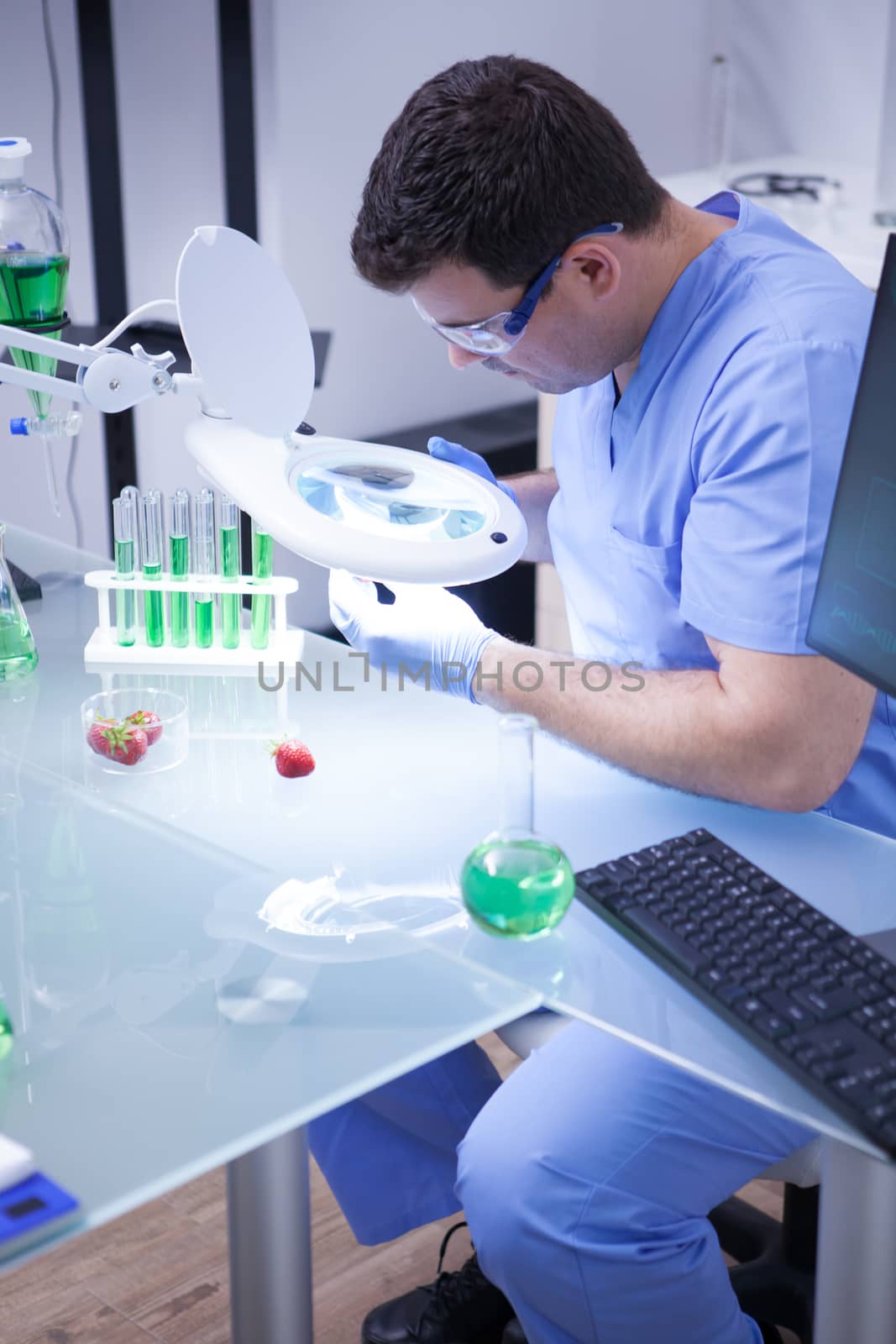 Young man in a research lab doing test on a strawberry in a agriculture research lab. test tubes.