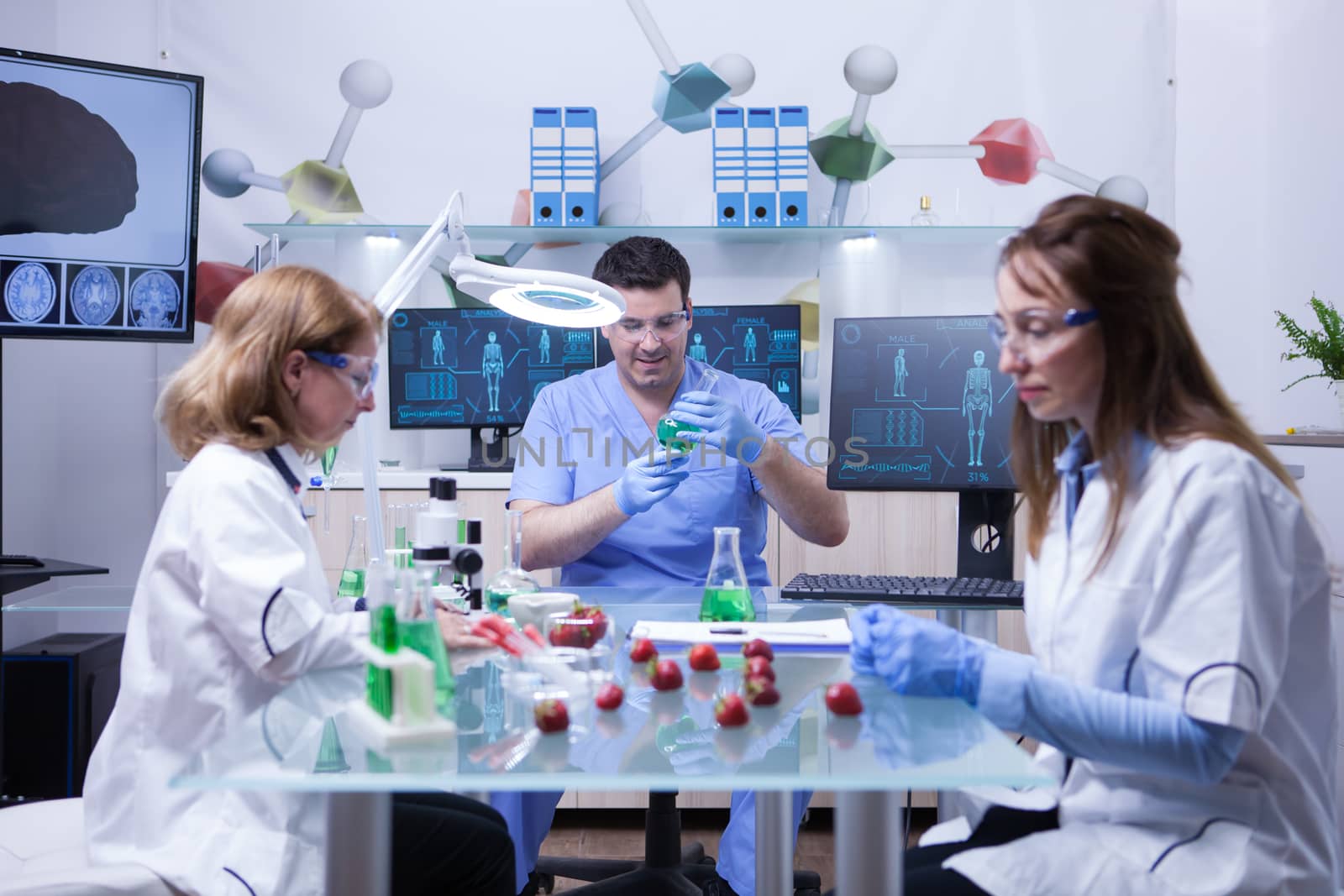 Young caucasian male scientist with two female scientist working in a lab research. Biologists working together.