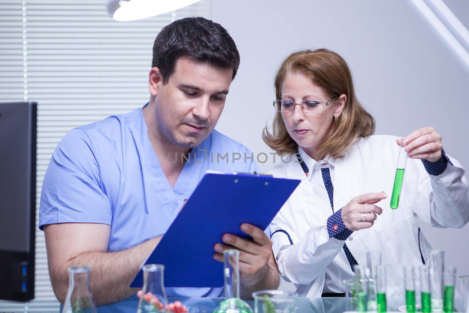 Middle age female sceintist telling her young assistant what notes to write down. Biologist team.