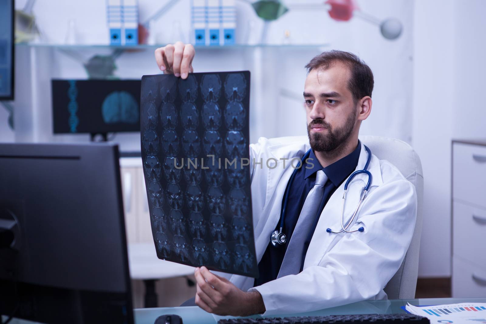 Portrait of handsome young doctor looking at a brain x ray. Doctor giving a diagnostic. Brain ct scan.
