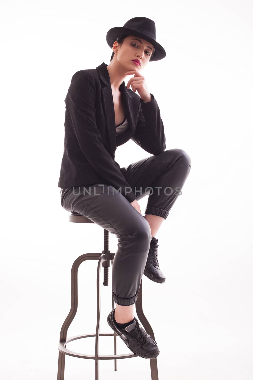 Stylish young woman in studio posing with confidence wearing a retro hat over white background in studio. Full body portrait.