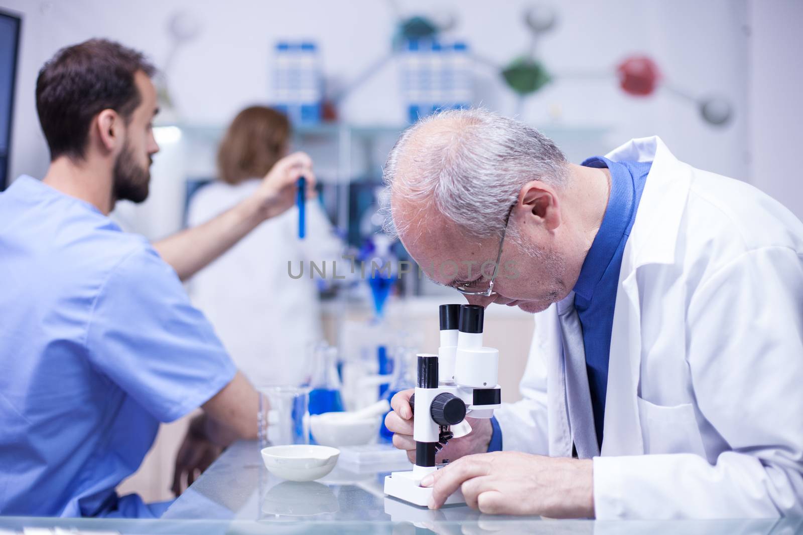 Senior technician making a discovery while working on microscope. Senior chemist in white coat.