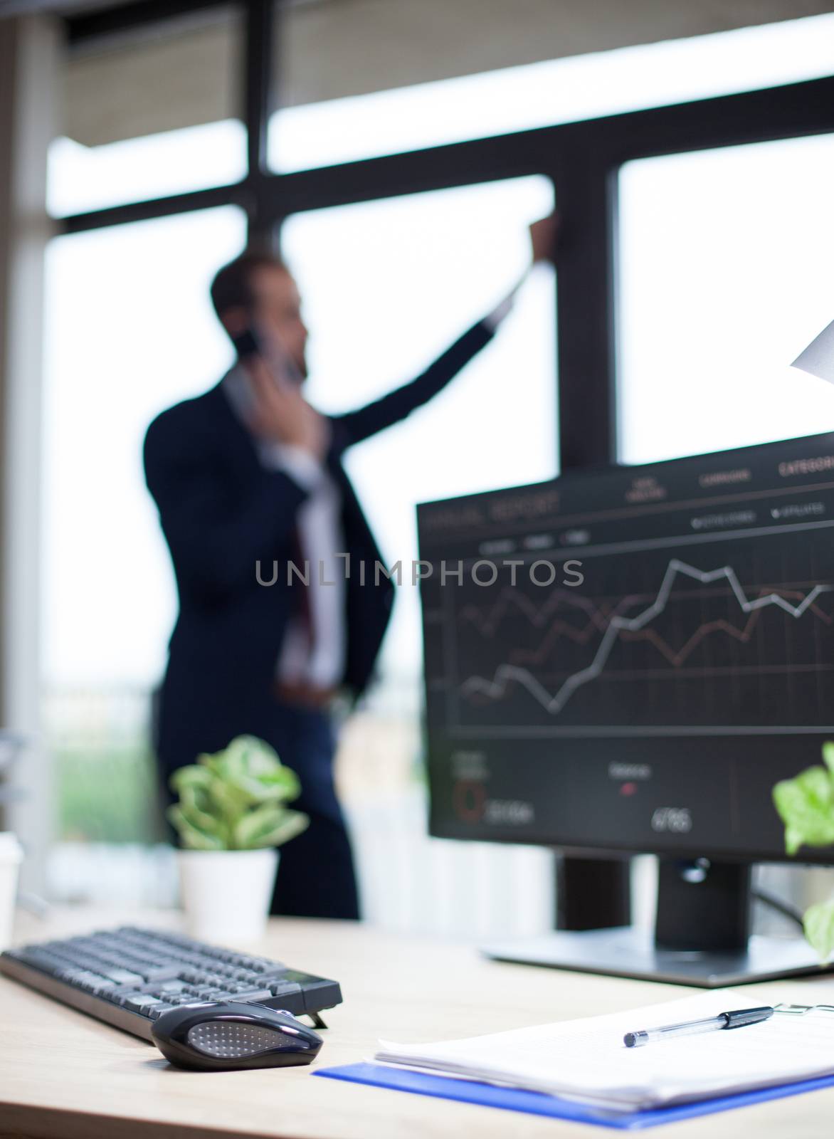 Data analysis displayed on marketing specialist computer in his office. Young entrepreneur in the background.