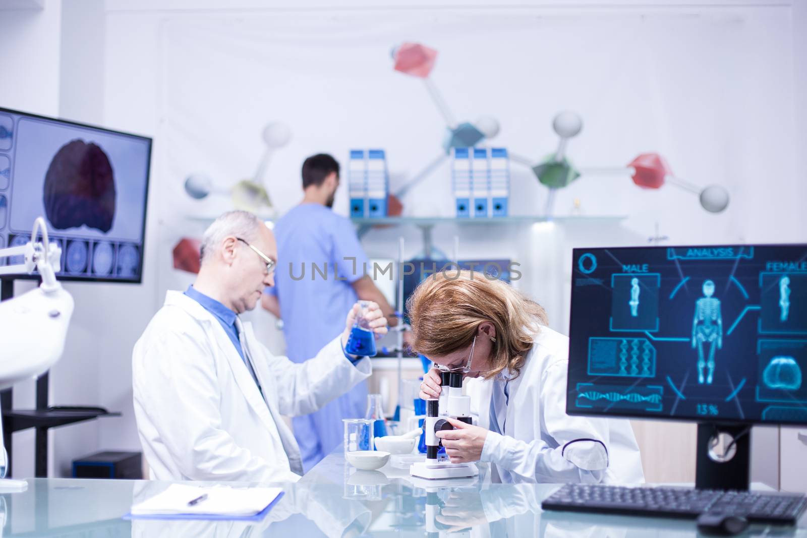 Team of scientist in working together in a laboratory. Senior chemist with test tube in his hand.