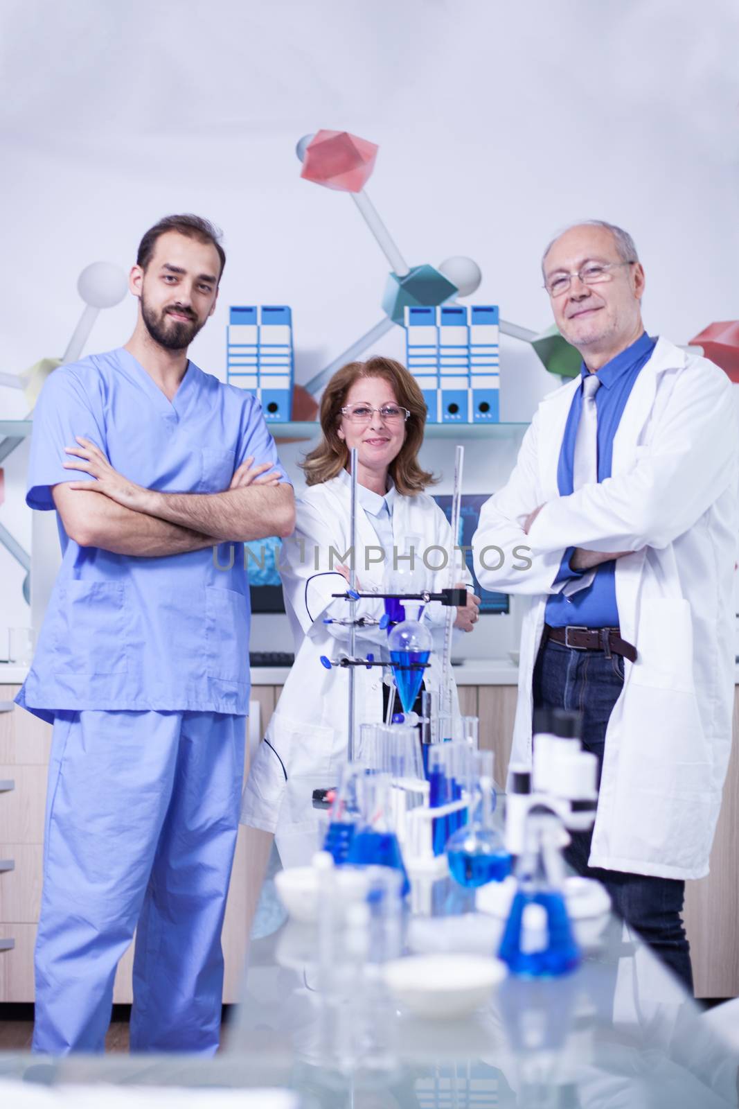 Female scientist smiling to the camera with her colleagues by her side in laboratory. Laboratory equipment.
