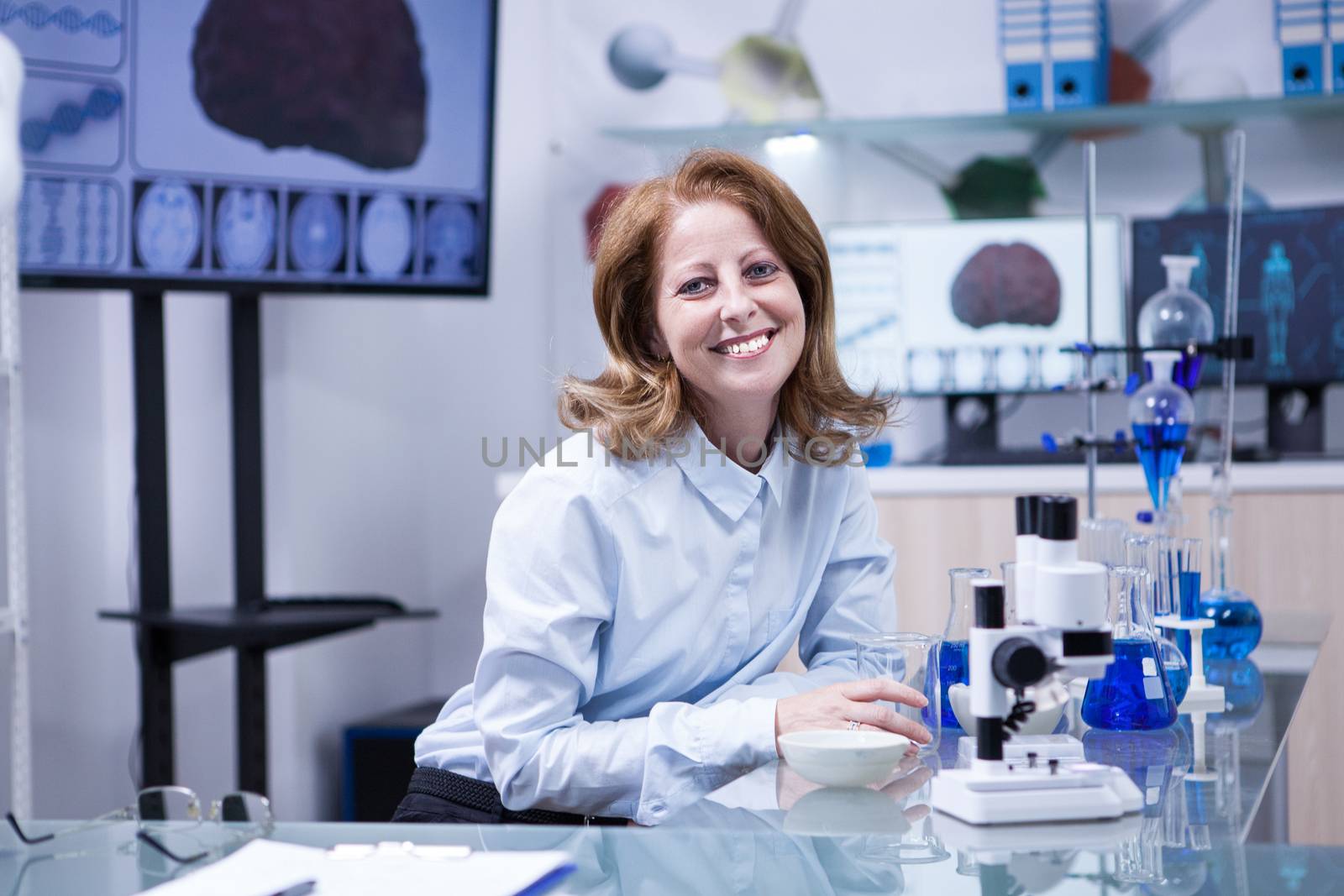 Smiling senior doctor woman working with microscope at laborator. Modern scientist.