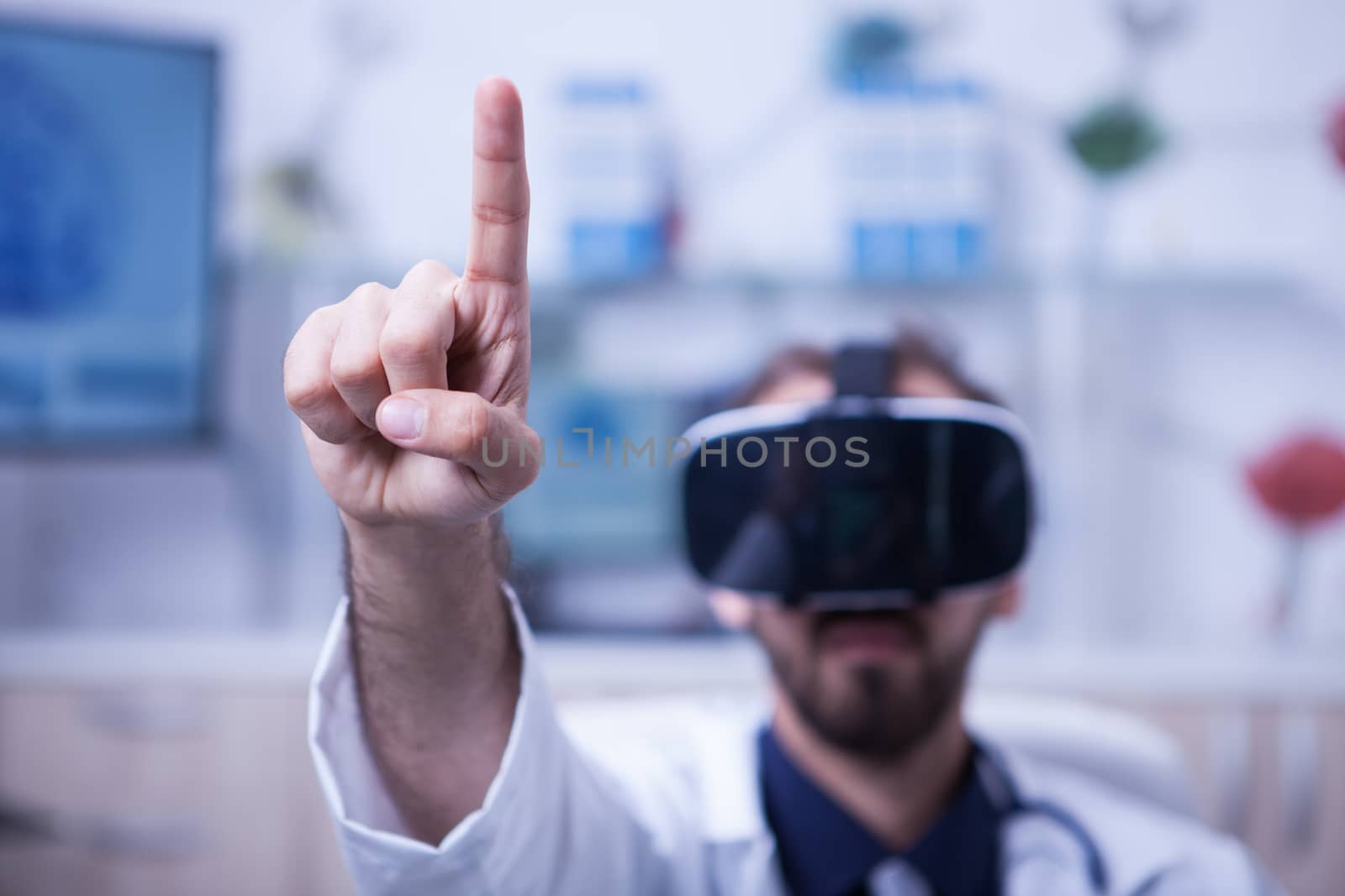 Close up of doctor pointing in the air with his finger wearing a virtual reality headset. Doctor in his medicine uniform.
