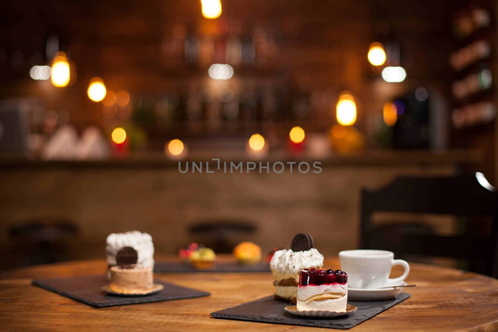 Tasty cup of coffee new delicious mini cakes with different shapes over a wooden table