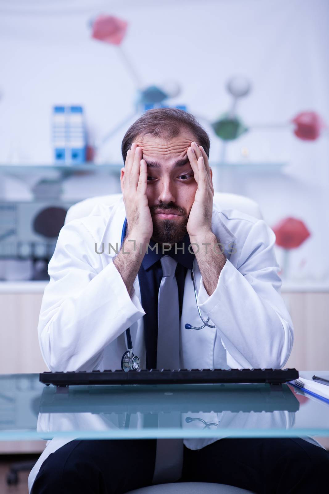 Portrait of young burnout doctor in his hospital cabinet. Young doctor overload of work at the hospital cabinet.