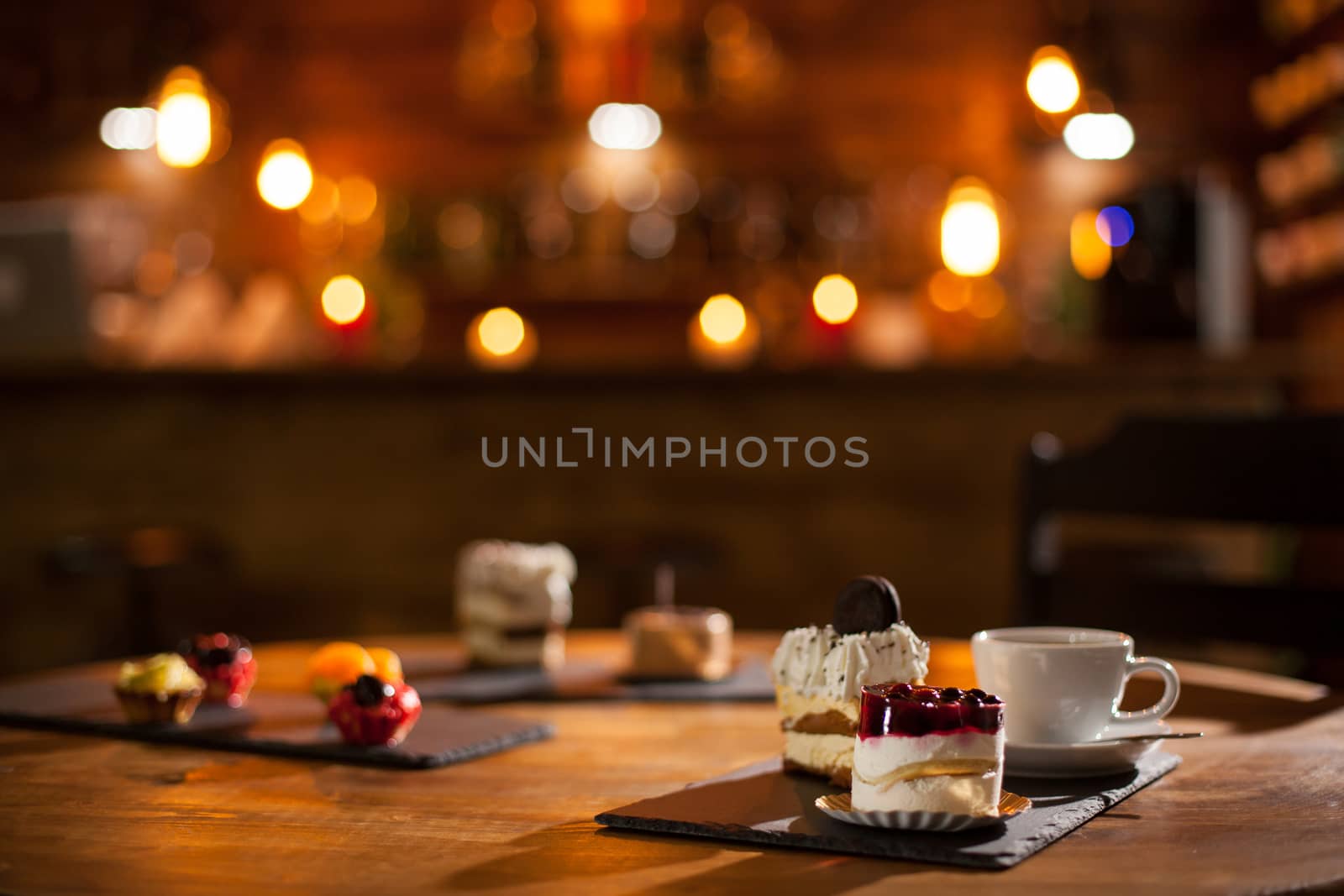 Gorgeous view of different cakes with different flavours over a wooden board in a coffee shop. Delicious variety of cakes in a coffee shop. Tasty cup of coffee.
