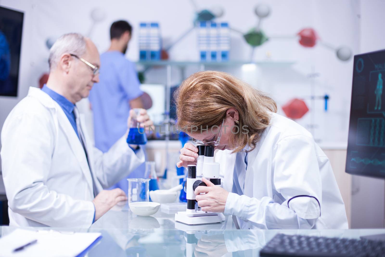 Senior female scientist working in a laboratory against diseases. Senior male scientist with a test tube in his hand.