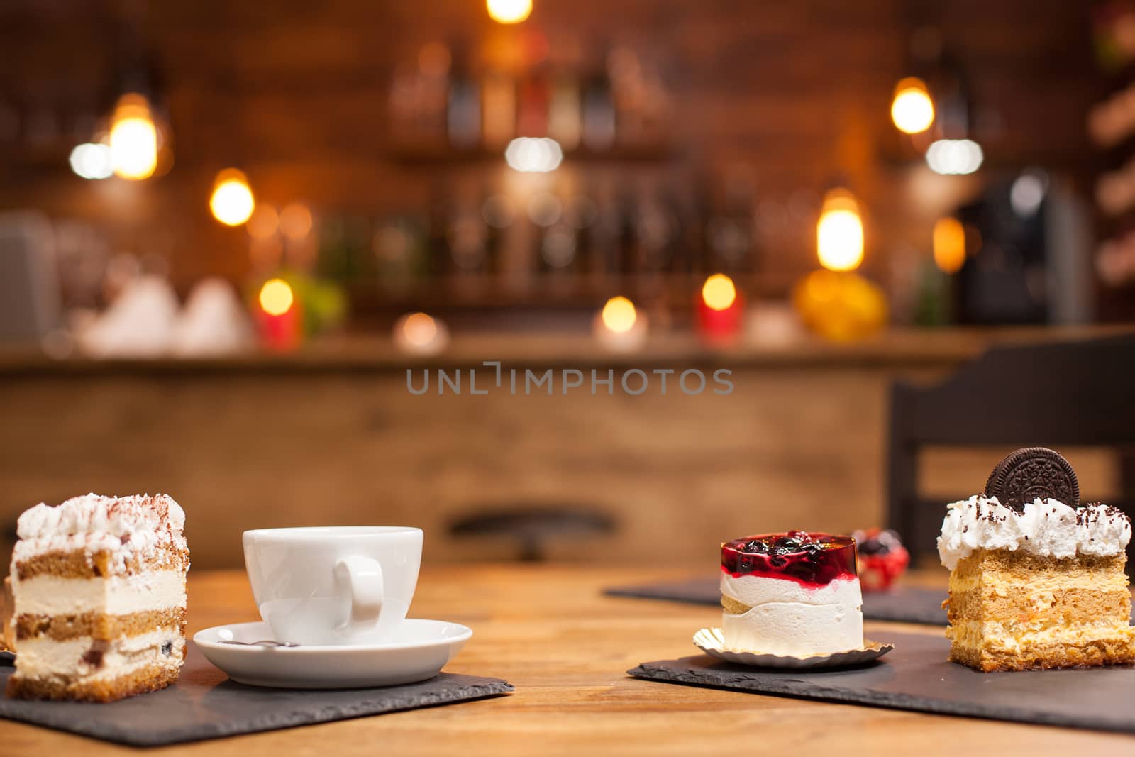 Set of different cakes and desserts freshly baked arranged on wooden table. Delicious cake with natural fruits on top. Cup of delicious coffee. Slice of cake with biscuit on top.