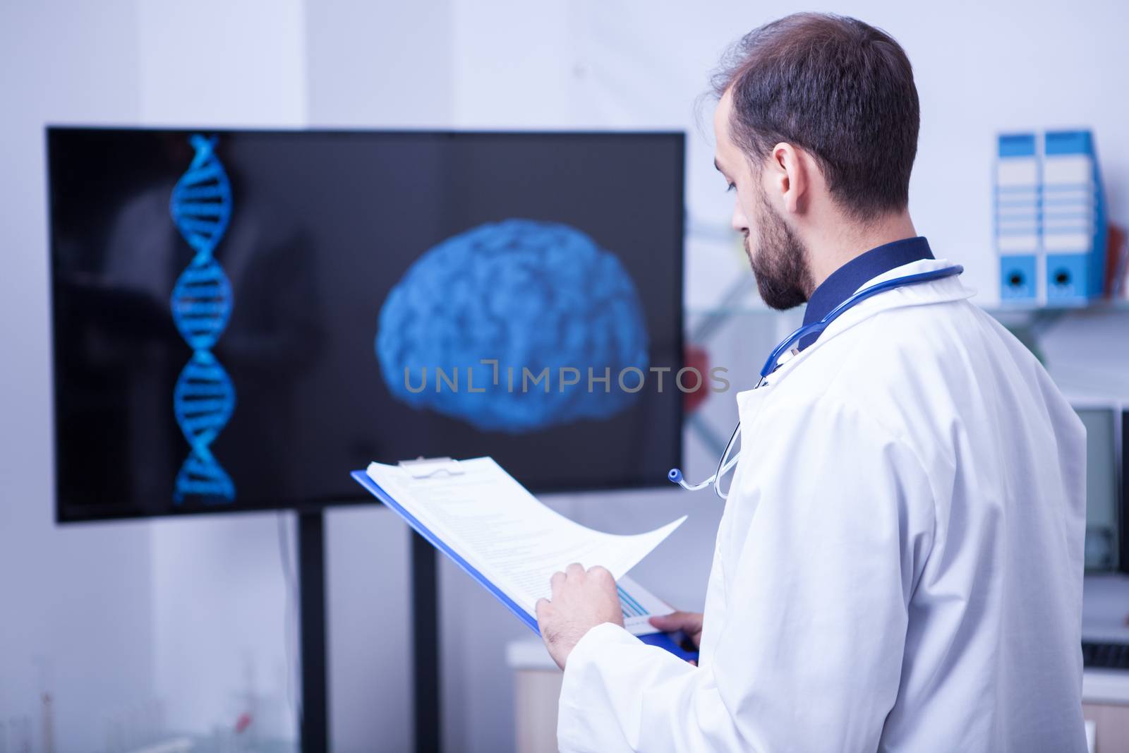 Specialist doctor in a laboratory looking at the scan of a brain holding a clipboard. Doctor with stethoscope around his neck.