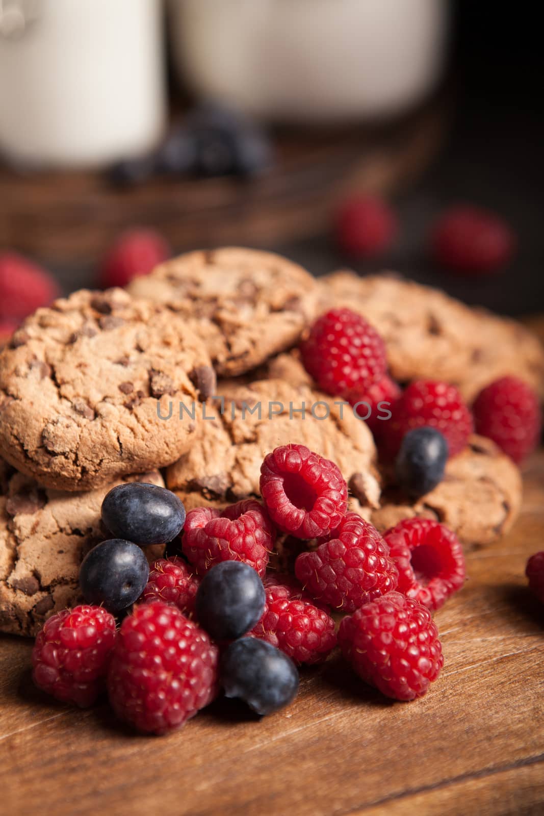 Close up photo of tasty blueberries with delicious chocolate chips. Chocolate cookies with milk.