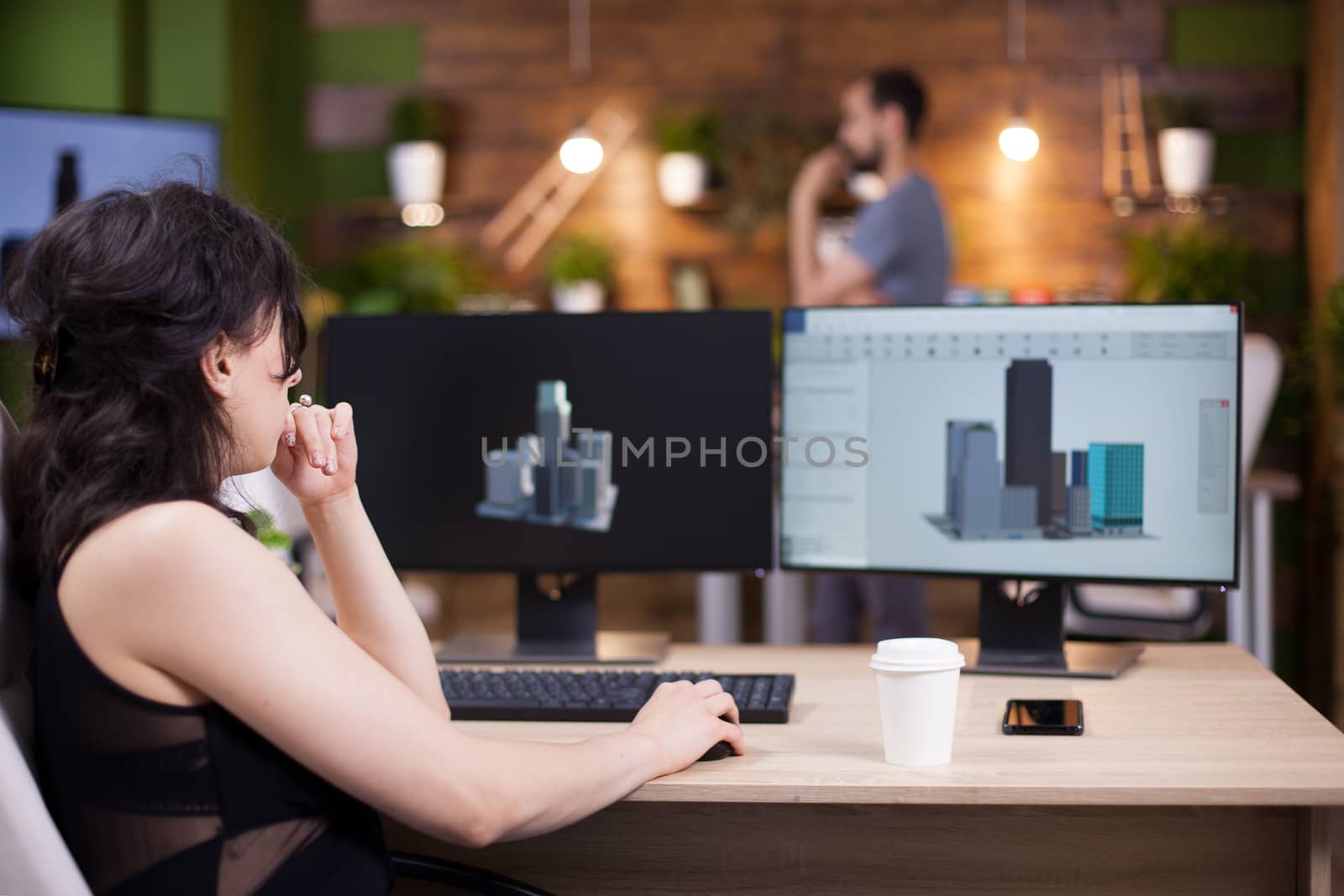 Back view of project leader working on her computer. Freelance female using moder technology in her office.