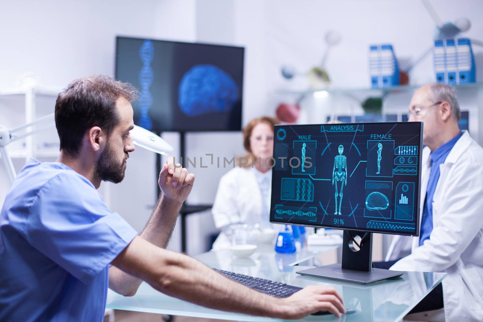 Portrait of young scientist looking at monitor computer checking male body. Team of engineers working in science laboratory.