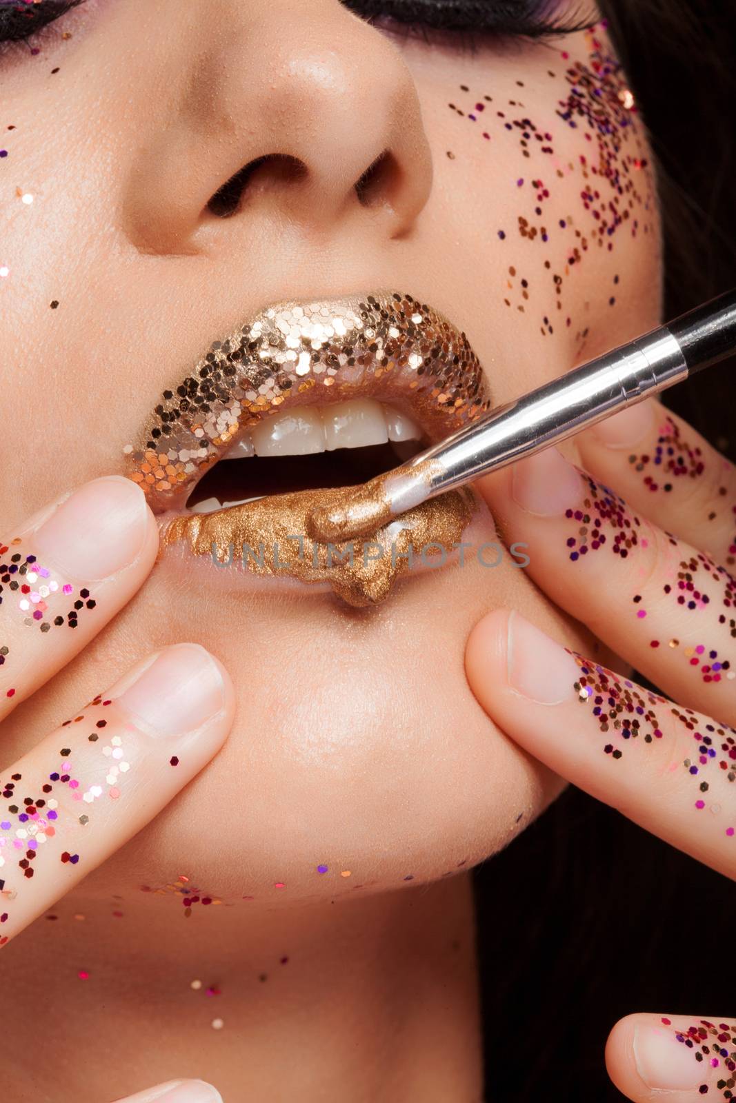 Fashion model with perfect lips covered with golden lipstick and glitter. Beauty shot. Sensual lips. Makeup artist.