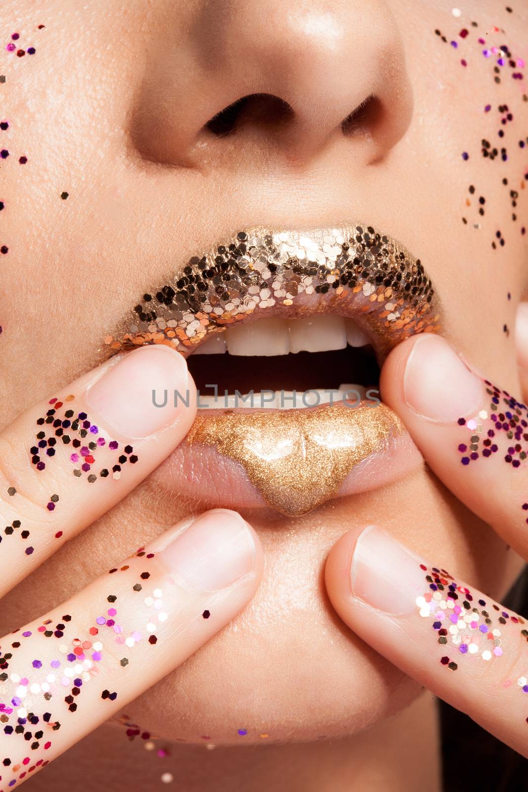 Woman with golden lips and glitter on her hands in studio. Beauty shot. Fashion shot. Beauty makeup.