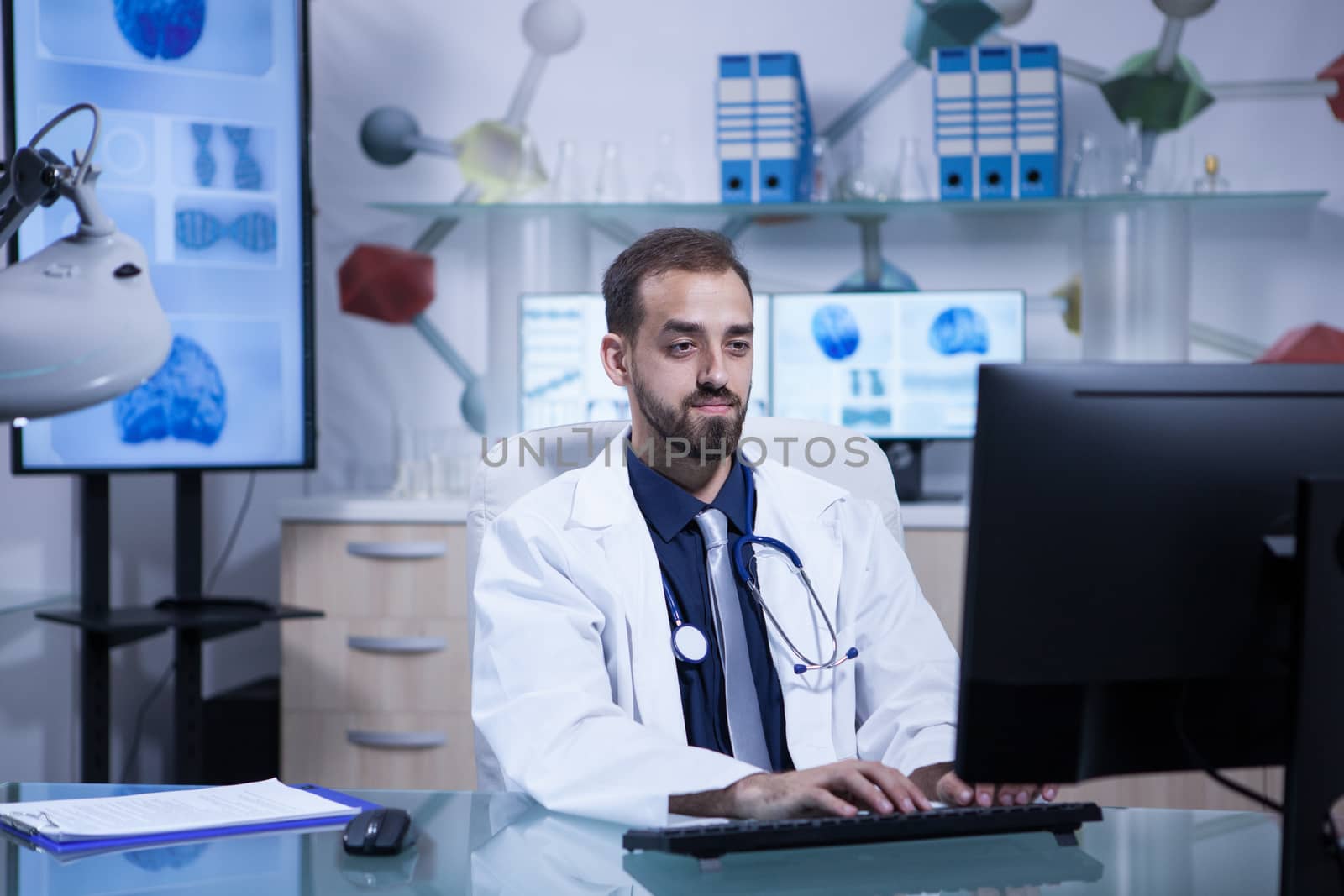 Portrait of young doctor in white coat working in his hospital office. Hospital technology.