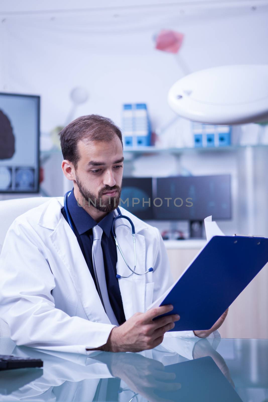 Doctor looking at the result of the analyzes of a patient on his clipboard. Specialist doctor in brain problems.