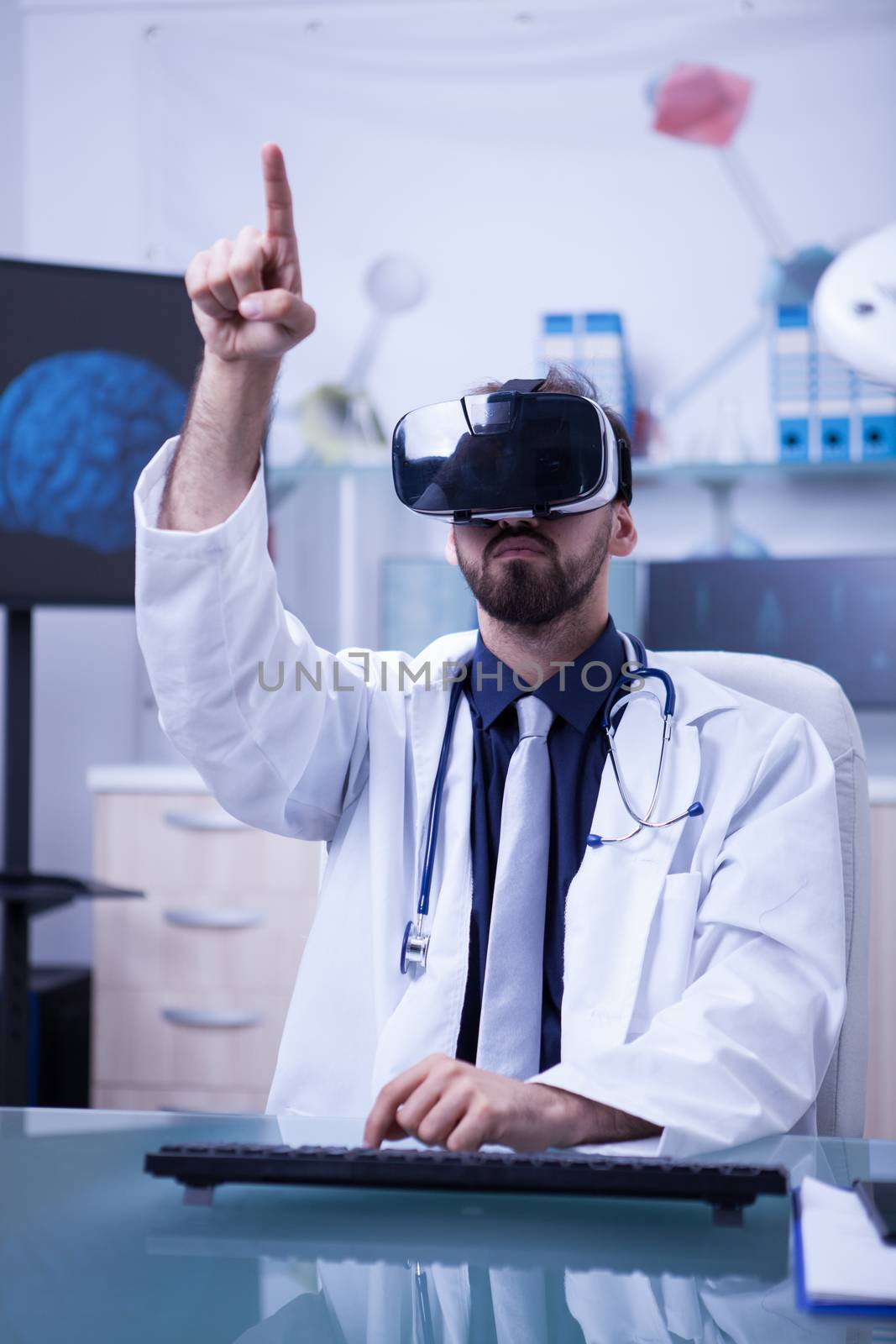 Young male doctor with virtual reality headset pointing by DCStudio