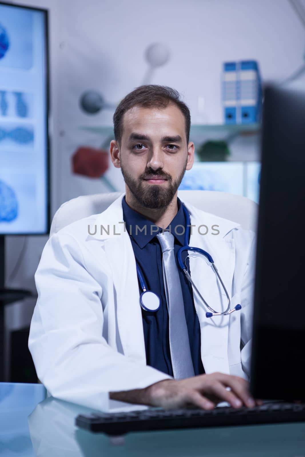 Portrait of attractive caucasian doctor looking into the camera sitting at his office. Handsome doctor.