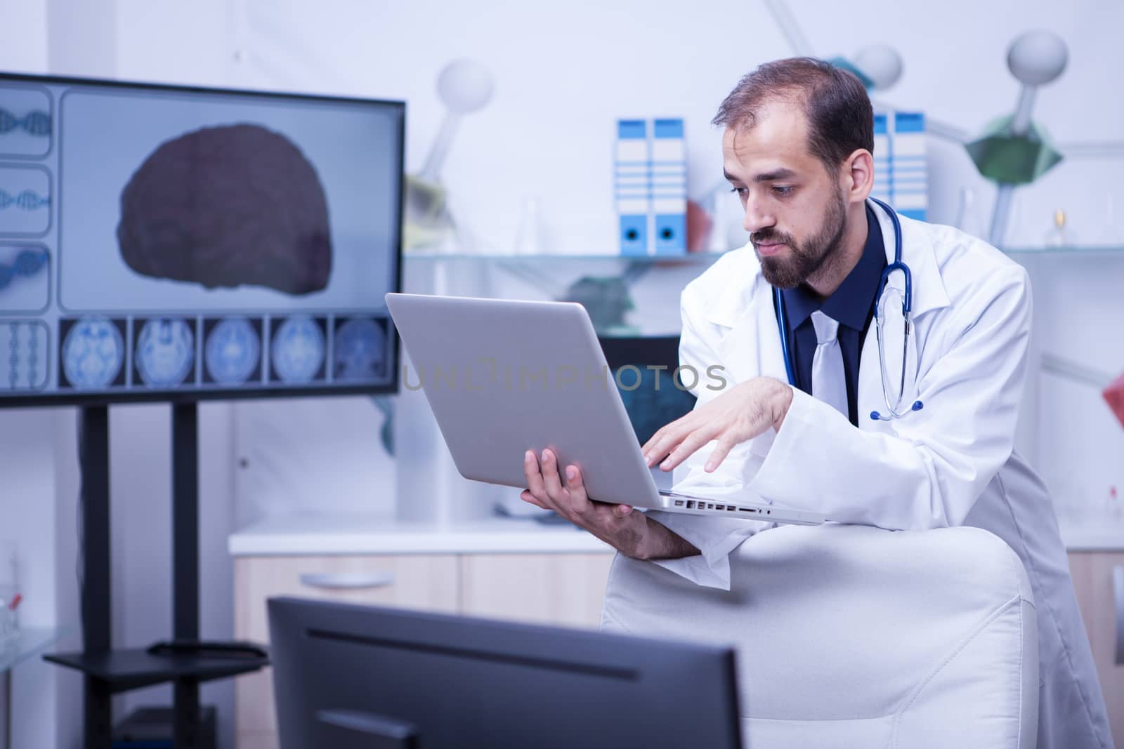 Doctor holding a laptop giving his expertise to another doctor. Doctor wearing a white coat.