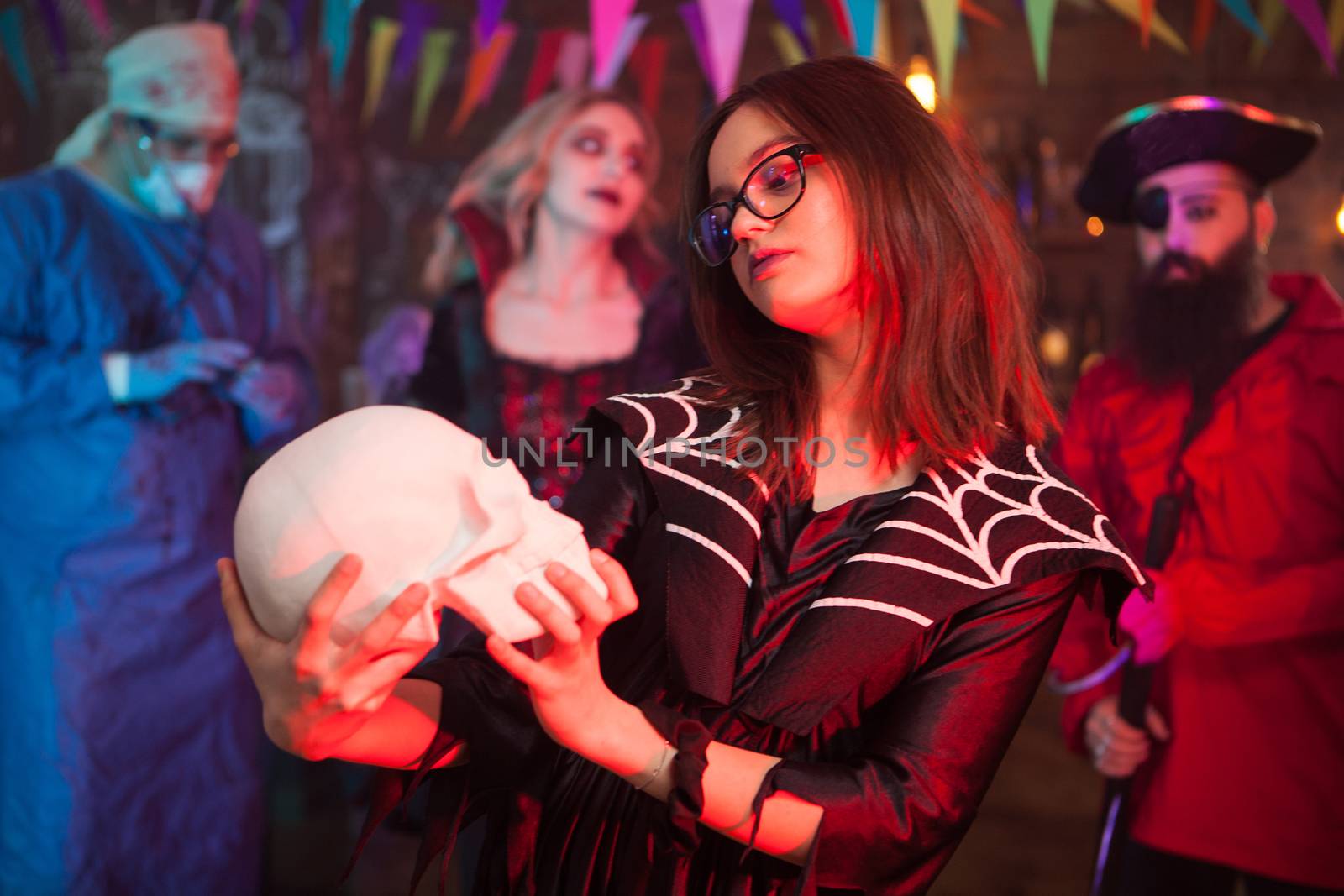 Little girl in a witch costume for halloween holding and admiring her human skull. Creepy witch.