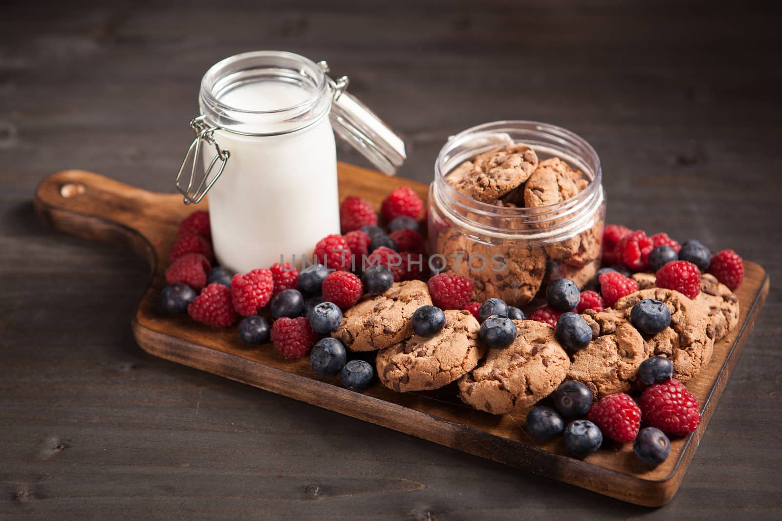 Fresh milk next to delicious chocolate chips with dark chocolate. Tasty biscuits.