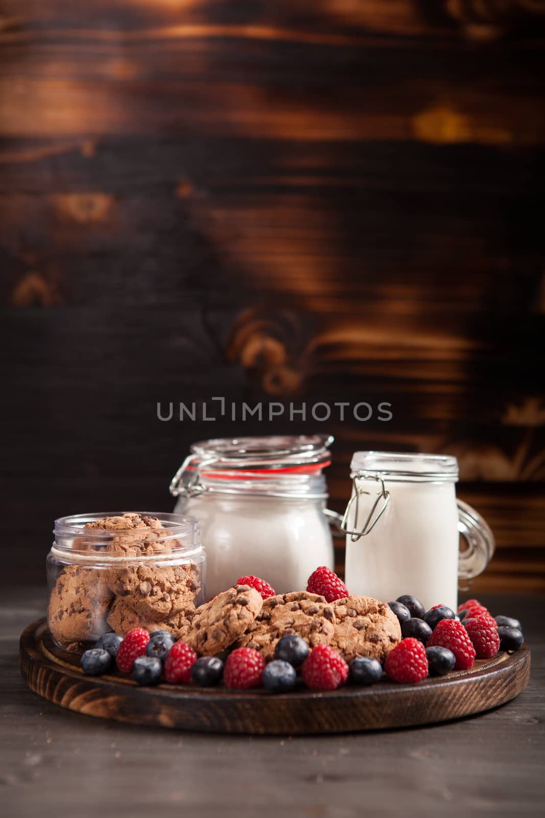 Freshly baked oatmeal biscuits with chocolate on wooden cutting board.