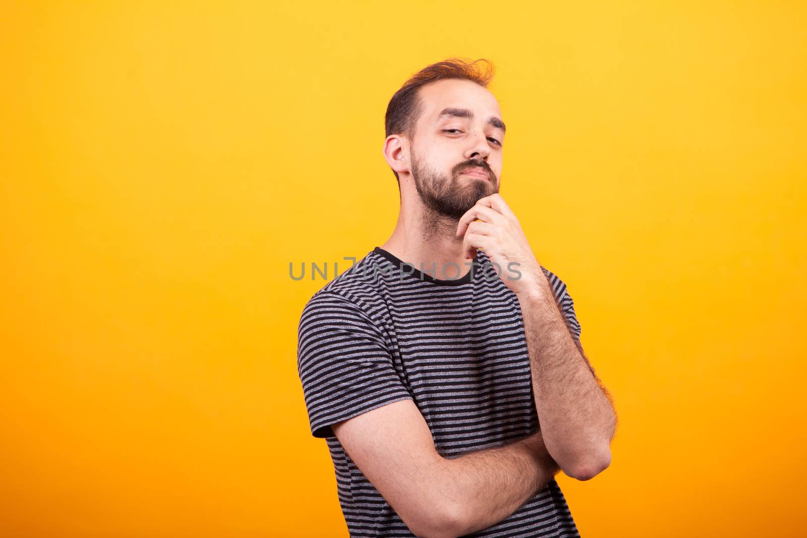 Portrait of thoughtful young man looking into the camera looking at the camera over yellow background.